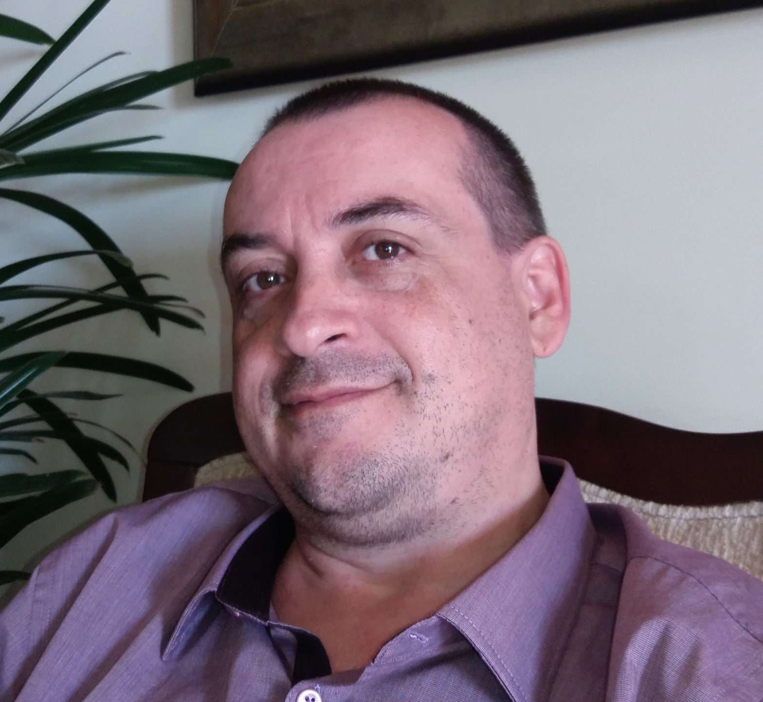 Psicoterapeuta Emilson Silva com camisa roxa e sorrindo